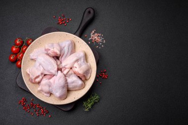 Taze çiğ tavuk kanatları. Tuz ve baharatlarla. Koyu beton bir arka planda pişirmeye hazır.