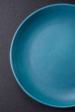 Beton zeminde güzel, boş, seramik bir tabak. Masada yemek servisi için mutfak gereçleri