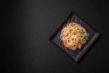 Lezzetli Asya yemekleri pilav eriştesi, tavuk, kuşkonmaz, biber, susam tohumu ve soya sosu ile koyu beton arka planda.