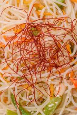 Lezzetli Asya yemekleri pilav eriştesi, tavuk, kuşkonmaz, biber, susam tohumu ve soya sosu ile koyu beton arka planda.