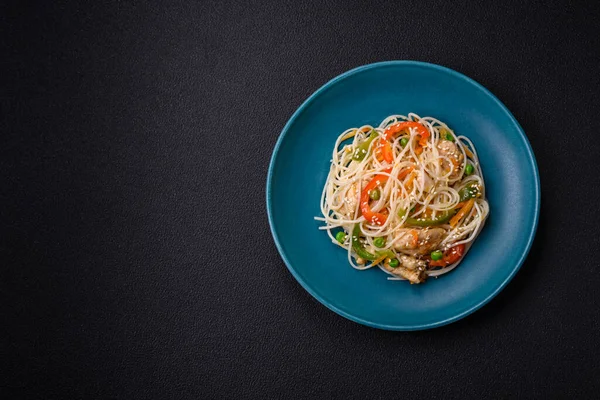 Lezzetli Asya yemekleri pilav eriştesi, tavuk, kuşkonmaz, biber, susam tohumu ve soya sosu ile koyu beton arka planda.