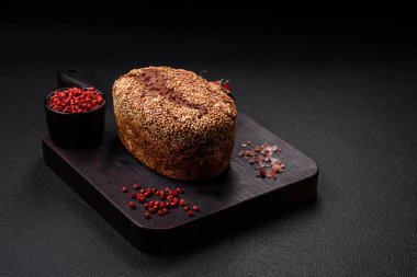 Koyu beton bir arka planda tohumları ve tahılları olan lezzetli çıtır çıtır kahverengi ekmek.