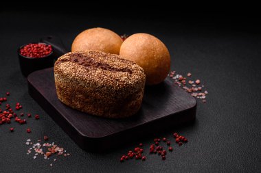 Koyu beton bir arka planda tohumları ve tahılları olan lezzetli çıtır çıtır kahverengi ekmek.