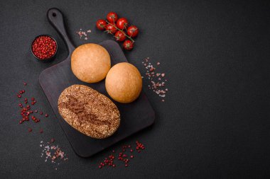 Koyu beton bir arka planda tohumları ve tahılları olan lezzetli çıtır çıtır kahverengi ekmek.