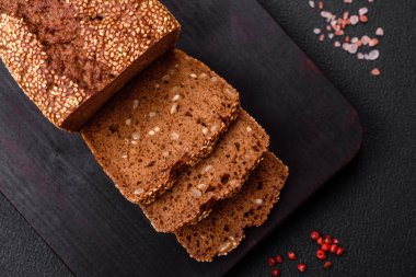 Koyu beton bir arka planda tohumları ve tahılları olan lezzetli çıtır çıtır kahverengi ekmek.