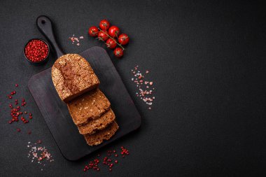 Koyu beton bir arka planda tohumları ve tahılları olan lezzetli çıtır çıtır kahverengi ekmek.