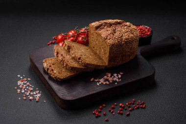 Koyu beton bir arka planda tohumları ve tahılları olan lezzetli çıtır çıtır kahverengi ekmek.