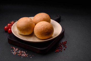 Lezzetli taze beyaz yuvarlak ekmek. Koyu beton arka planda tohumlar ve tahıllar var.