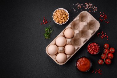 Kutuda çiğ tavuk yumurtası, kiraz domatesleri, nohut, baharat, tuz ve otlar. Lezzetli, besleyici bir kahvaltı için gerekli malzemeler.