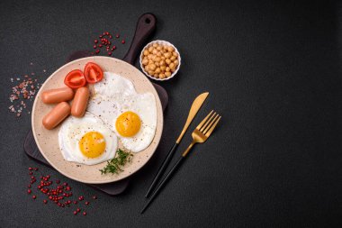 Kızarmış tavuk yumurtası, sosis, vişneli domates, nohut, baharat, tuz ve ot. Lezzetli besleyici kahvaltı.