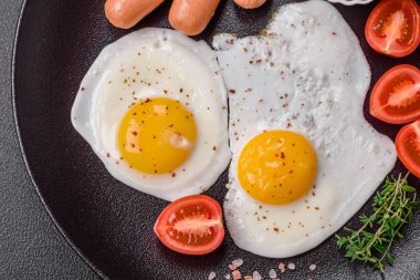 Kızarmış tavuk yumurtası, sosis, vişneli domates, nohut, baharat, tuz ve ot. Lezzetli besleyici kahvaltı.