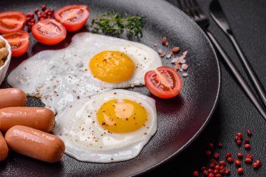 Kızarmış tavuk yumurtası, sosis, vişneli domates, nohut, baharat, tuz ve ot. Lezzetli besleyici kahvaltı.