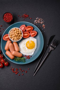 Kızarmış tavuk yumurtası, sosis, vişneli domates, nohut, baharat, tuz ve ot. Lezzetli besleyici kahvaltı.