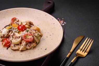 Tavuklu taze salata, bıldırcın yumurtası, kiraz domatesleri, marul, tuz ve baharatlar koyu beton arka planda.