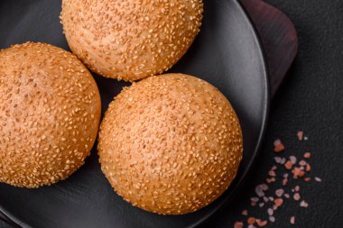 Lezzetli taze beyaz yuvarlak ekmek. Koyu beton arka planda tohumlar ve tahıllar var.