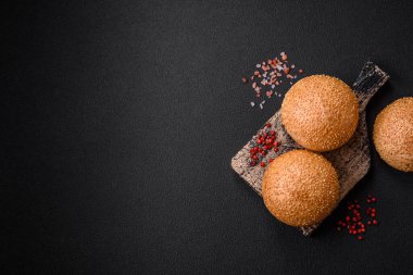 Lezzetli taze beyaz yuvarlak ekmek. Koyu beton arka planda tohumlar ve tahıllar var.