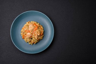 Koyu beton arka planda tavuk, havuç, böğürtlen, baharat ve bitkilerle nefis Özbek pilavı