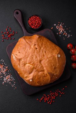 Koyu beton bir arka planda tohumları ve tahılları olan lezzetli çıtır çıtır kahverengi ekmek.