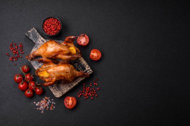 Kavrulmuş bıldırcın, keklik ya da portakalla doldurulmuş koyu beton arka planda baharat ve otlarla dolu güvercin.