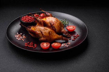 Kavrulmuş bıldırcın, keklik ya da portakalla doldurulmuş koyu beton arka planda baharat ve otlarla dolu güvercin.