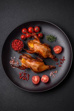 Kavrulmuş bıldırcın, keklik ya da portakalla doldurulmuş koyu beton arka planda baharat ve otlarla dolu güvercin.