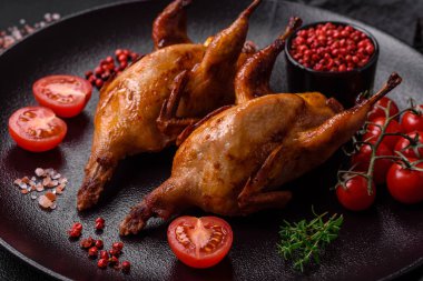 Kavrulmuş bıldırcın, keklik ya da portakalla doldurulmuş koyu beton arka planda baharat ve otlarla dolu güvercin.