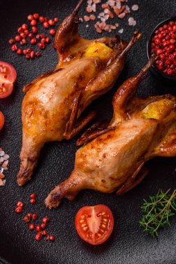 Kavrulmuş bıldırcın, keklik ya da portakalla doldurulmuş koyu beton arka planda baharat ve otlarla dolu güvercin.