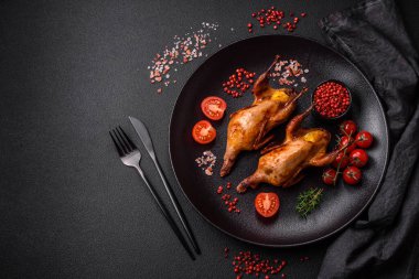 Kavrulmuş bıldırcın, keklik ya da portakalla doldurulmuş koyu beton arka planda baharat ve otlarla dolu güvercin.