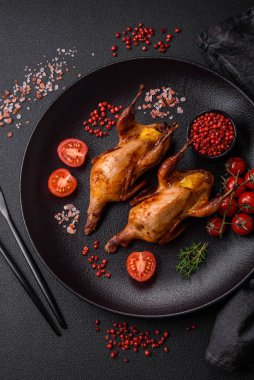 Kavrulmuş bıldırcın, keklik ya da portakalla doldurulmuş koyu beton arka planda baharat ve otlarla dolu güvercin.