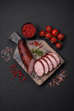 Tuzlu ve baharatlı lezzetli füme sosis koyu beton arka planda dilimler halinde kesilmiş.