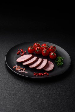 Tuzlu ve baharatlı lezzetli füme sosis koyu beton arka planda dilimler halinde kesilmiş.