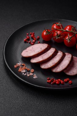 Tuzlu ve baharatlı lezzetli füme sosis koyu beton arka planda dilimler halinde kesilmiş.
