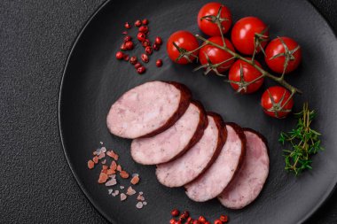 Tuzlu ve baharatlı lezzetli füme sosis koyu beton arka planda dilimler halinde kesilmiş.