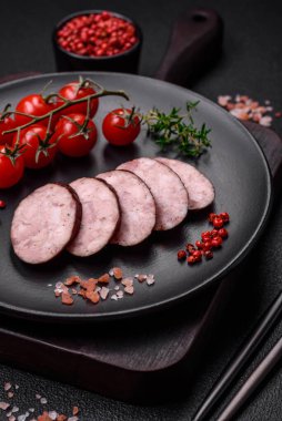 Tuzlu ve baharatlı lezzetli füme sosis koyu beton arka planda dilimler halinde kesilmiş.