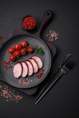 Tuzlu ve baharatlı lezzetli füme sosis koyu beton arka planda dilimler halinde kesilmiş.