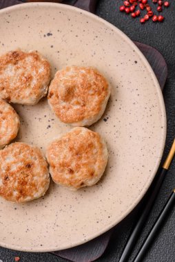Kızarmış et köftesi, domuz eti ya da tuzlu tavuk, baharat ve ottan oluşan koyu beton bir arka planda.