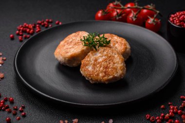 Kızarmış et köftesi, domuz eti ya da tuzlu tavuk, baharat ve ottan oluşan koyu beton bir arka planda.