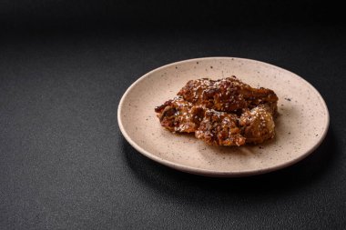 Lezzetli ızgara tavuk kanatları. Tuz, baharat ve teriyaki soslu. Koyu beton arka planda.