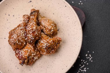 Lezzetli ızgara tavuk kanatları. Tuz, baharat ve teriyaki soslu. Koyu beton arka planda.