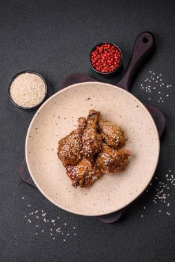 Lezzetli ızgara tavuk kanatları. Tuz, baharat ve teriyaki soslu. Koyu beton arka planda.
