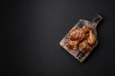 Lezzetli ızgara tavuk kanatları. Tuz, baharat ve teriyaki soslu. Koyu beton arka planda.