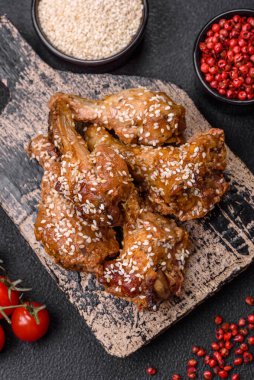 Lezzetli ızgara tavuk kanatları. Tuz, baharat ve teriyaki soslu. Koyu beton arka planda.