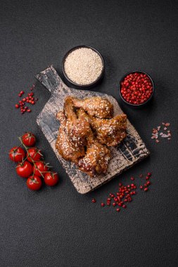 Lezzetli ızgara tavuk kanatları. Tuz, baharat ve teriyaki soslu. Koyu beton arka planda.