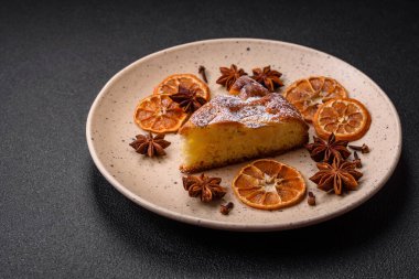 Elma ya da armutla pişirilmiş bir parça ev yapımı turta, üzerine toz serpiştirilmiş, koyu beton bir arka plan.