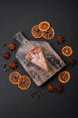 Elma ya da armutla pişirilmiş bir parça ev yapımı turta, üzerine toz serpiştirilmiş, koyu beton bir arka plan.