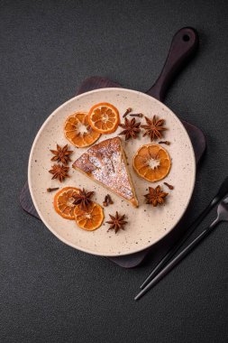 Elma ya da armutla pişirilmiş bir parça ev yapımı turta, üzerine toz serpiştirilmiş, koyu beton bir arka plan.