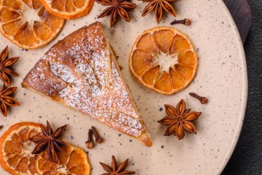 Elma ya da armutla pişirilmiş bir parça ev yapımı turta, üzerine toz serpiştirilmiş, koyu beton bir arka plan.