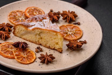 Elma ya da armutla pişirilmiş bir parça ev yapımı turta, üzerine toz serpiştirilmiş, koyu beton bir arka plan.