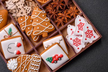 Koyu beton bir masada seramik tabakta farklı renklerde güzel Noel kurabiyeleri.
