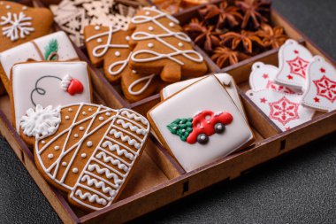 Koyu beton bir masada seramik tabakta farklı renklerde güzel Noel kurabiyeleri.